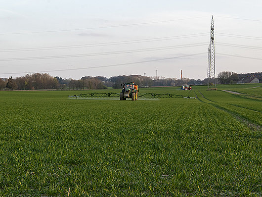 Ein Traktor spritzt ein Feld mit einer Spritze.